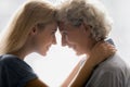 Closeup profile faces grownup daughter touch foreheads with aged mother