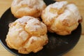 Closeup the Profiteroles, Fluffy French Choux Pastries with Icing Sugar on a Black Plate Royalty Free Stock Photo