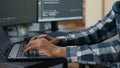 Closeup of programer hands typing machine learning code on laptop keyboard in front of computer screens