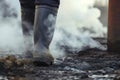 closeup of protective boots walking near smoking smokestack Royalty Free Stock Photo