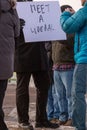 Closeup of a protester holding a liberal sign banner