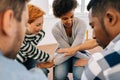 Closeup of psychologist and multicultural group of men and women sitting in circle and holding crosswise hands therapy Royalty Free Stock Photo