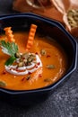 Closeup pumpkin cream soup in blue plate with pumpkin seeds on gray background, seasonal autumn dish