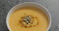 Closeup pumpkin cream soup in white bowl on terrazzo countertop