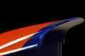 A closeup of a race cars rear spoiler the details of its curve and the colorful paint finishing can be seen. Speed drive