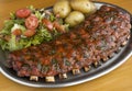 Closeup of a rack of ribs with a side of salad and potatoes Royalty Free Stock Photo