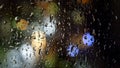 Closeup of rain droplets and streams flowing down the window at night. Colorful bokeh lights on the background Royalty Free Stock Photo