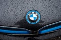 Closeup of rain drops on BMW logo on black car parked in the street