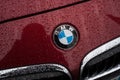 Closeup of rain drops on bmw logo on red car front