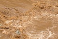 Closeup of rapid flow of brown water in the muddy river