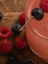 Closeup of a raspberry and blueberry mixed cocktail drink with a wooden background