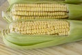 Closeup of raw corn cobs with straw over wood Royalty Free Stock Photo