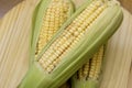 Closeup of raw corn cobs with straw over wood Royalty Free Stock Photo