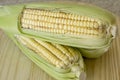 Closeup of raw corn cobs with straw over wood