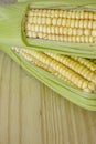 Closeup of raw corn cobs with straw over wood Royalty Free Stock Photo