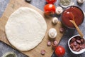 Top view of raw dough for pizza on the cutting board and various ingredients for it.Tomatoes, sauce, mushrooms, oil, herbs, sausag Royalty Free Stock Photo