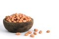 Closeup raw dry peanuts seed on brown wooden bowl isolated / cutout in white background with studio lighting