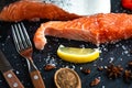 Closeup raw salmon fish fillet with lemon, spices prepares for cook on slate cutting board. Royalty Free Stock Photo