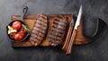 Closeup ready to eat steak Top Blade beef breeds of black Angus with grill tomato, garlic and on a wooden Board. The Royalty Free Stock Photo