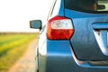 Closeup of rear red taillight and mirror of new clean blue SUV off-road car on rural road Royalty Free Stock Photo