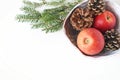 Closeup of red apple fruit and pine cones in ceramic bowl and spruce tree branches on white table background. Christmas Royalty Free Stock Photo