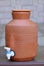 Closeup the red brown earthen clay filter with blue white tap on the table soft focus natural grey brown background