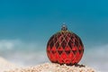 Closeup of Red Christmas Ball on the Tropical Beach, Winter Holiday Concept Royalty Free Stock Photo