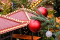Closeup of Red Christmas balls and garland on a branches of natural New Year tree on festive decorated city market outdoors at Royalty Free Stock Photo