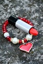 closeup the red color lipstick silver black tube with red white plastic beads bracelet soft focus natural grey brown background Royalty Free Stock Photo