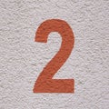 Closeup of red-colored number 2 on white concrete wall background Royalty Free Stock Photo