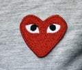 Closeup of a red embroidered heart with eyes on a gray fabric