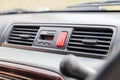 Closeup of a red emergency light button with a white triangle between the air conditioning grilles on the dashboard in the Royalty Free Stock Photo
