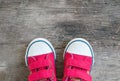 Closeup red fabric sneakers of kid on old wood floor textured background in top view with copy space Royalty Free Stock Photo