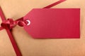 Closeup red gift tag and ribbon, brown parcel wrapping paper background Royalty Free Stock Photo