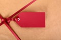 Closeup red gift tag and ribbon, brown parcel wrapping paper background Royalty Free Stock Photo