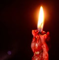 Closeup of red lit candle isolated on dark red background, fire, flame