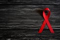 Closeup red ribbon awareness on black wooden table background Royalty Free Stock Photo
