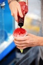 A closeup of a person making a colorful red snow cone. Royalty Free Stock Photo