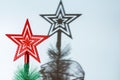 Closeup of a red star on top of a Christmas tree throwing a shadow on the wall