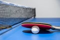 Closeup red table tennis paddle white ball and a net Royalty Free Stock Photo