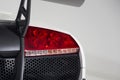 Closeup of a red tail light of a white luxury car isolated on a grey background Royalty Free Stock Photo