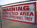Closeup of a red warning restricted area authorized personnel only sign on a chain-link fence
