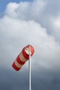A red and white striped windsock against a stormy sky Royalty Free Stock Photo