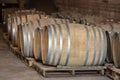 Closeup red wine glass on background of wooden oak barrels stacked in straight rows in order in cellar of wine, vault. Concept Royalty Free Stock Photo