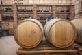 Closeup red wine glass on background of wooden oak barrels stacked in straight rows in order in cellar of wine, vault. Concept Royalty Free Stock Photo