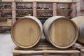 Closeup red wine glass on background of wooden oak barrels stacked in straight rows in order in cellar of wine, vault. Concept Royalty Free Stock Photo