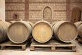 Closeup red wine glass on background of wooden oak barrels stacked in straight rows in order in cellar of wine, vault. Concept Royalty Free Stock Photo