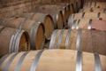 Closeup red wine glass on background of wooden oak barrels stacked in straight rows in order in cellar of wine, vault. Concept Royalty Free Stock Photo