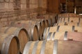 Closeup red wine glass on background of wooden oak barrels stacked in straight rows in order in cellar of wine, vault. Concept Royalty Free Stock Photo