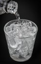 Closeup of puring water Into glass with ice on dark background Royalty Free Stock Photo